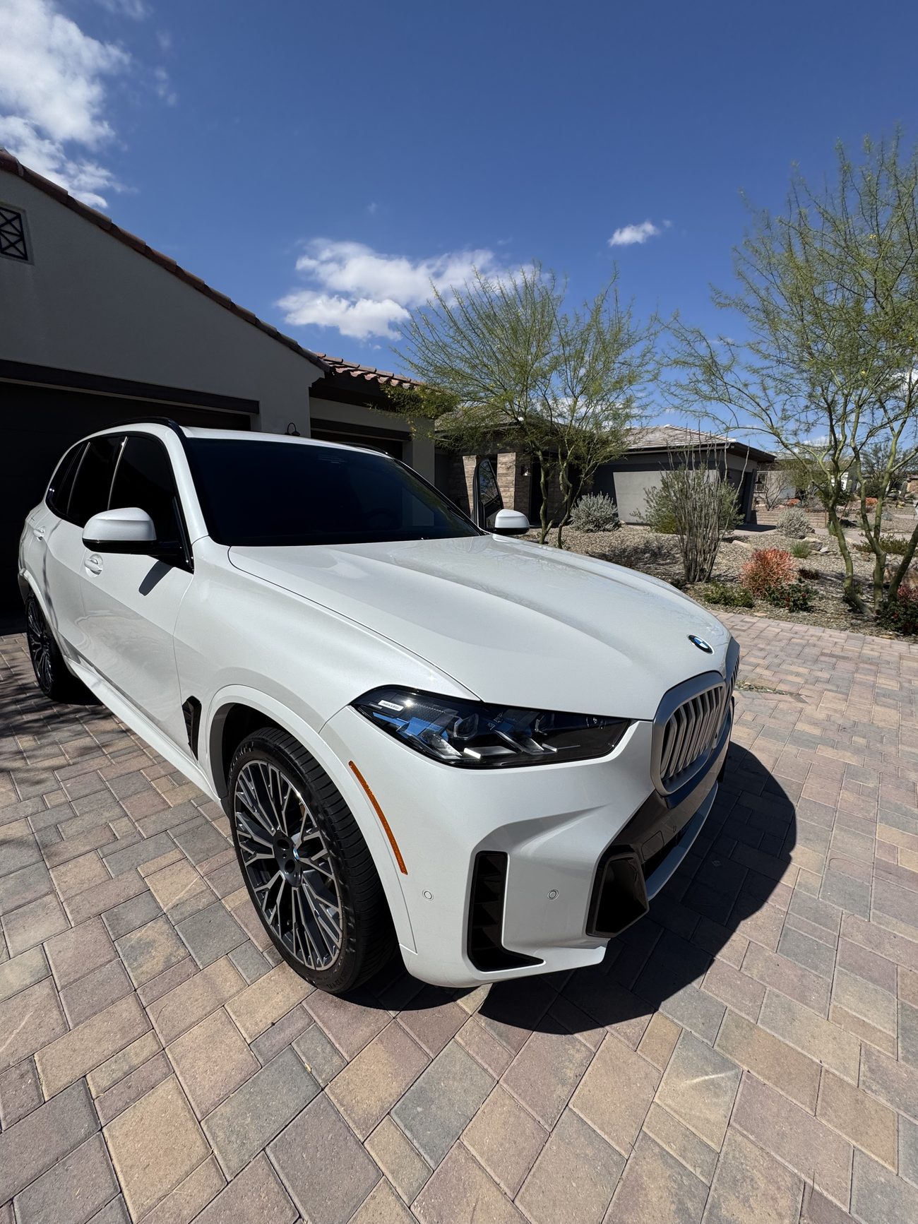 Detailed white BMW X7 SUV parked on a paver driveway