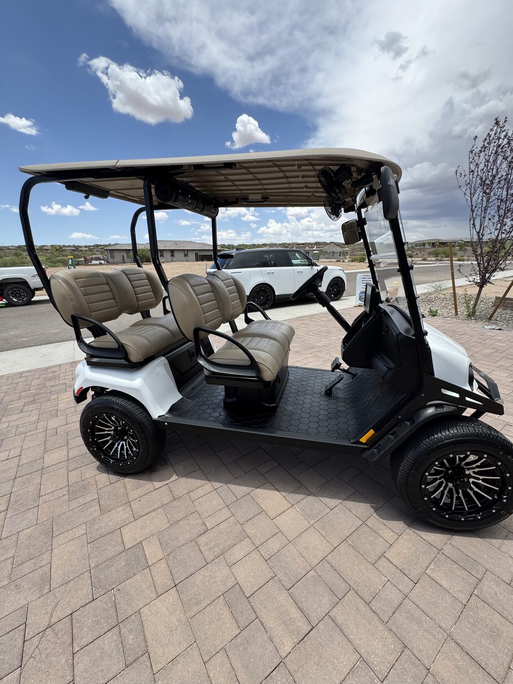 Clean, freshly detailed white golf cart on a paver driveway
